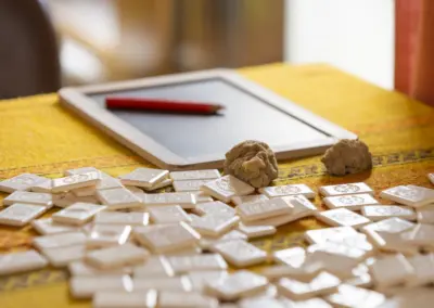 Tablet mit rotem Stylus auf gelbem Tisch, verstreute weiße Schokoladenstücke und Teigklumpen.