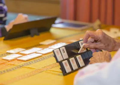 Nahaufnahme: Ältere Hände bedienen eine Registrierkasse mit großen Tasten; Karten liegen daneben.
